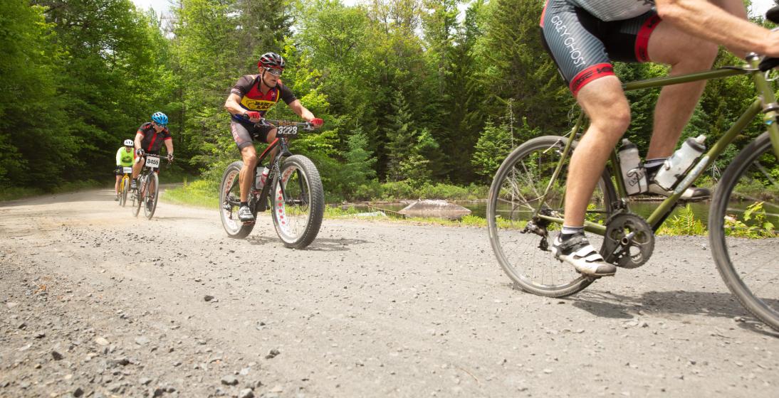 A group of cyclists ride on a gravel path. 