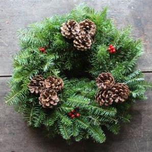 A wreath made from Balsam fir branches and decorated with pinecones and red berries