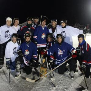 Two teams of hockey players posing for a photo on the ice