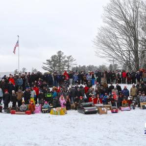 A large group of people who attended last year's carnival posing for a photo with cardboard sleds in front