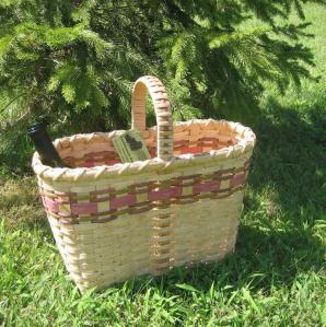 a hand-made wine basket with 2 bottles of wine in it sitting on green grass