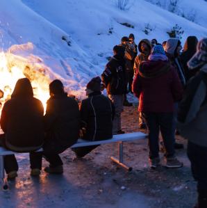 a group of people around a bon fire out in the snow