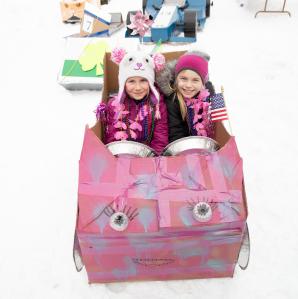 two girls in a pink cardboard sled