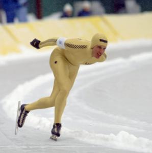 A man is a speedskating uniform racing around an ice track