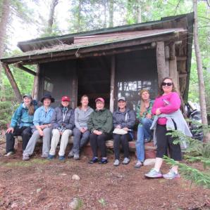 Several ladies sitting in a lean to for a group phot at great camp sagamore