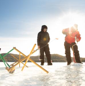 Two ice fishermen setting up gear on a frozen lake.