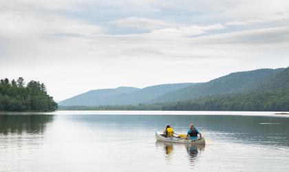 Two people in a canoe paddle across Lewey Lake.