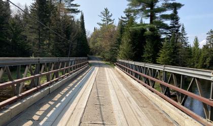 A wooden bridge leading to a wooded trail.