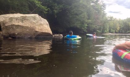 group of rafters floating by a big rock in the river