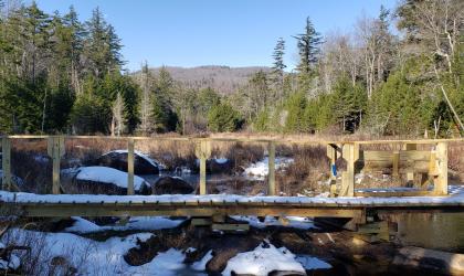 A wooden bridge lightly covered in snow