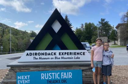 Two children standing in front of the ADX sign