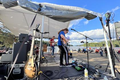 A band playing under a pop-up tent to a crowd at the Long Lake public beach