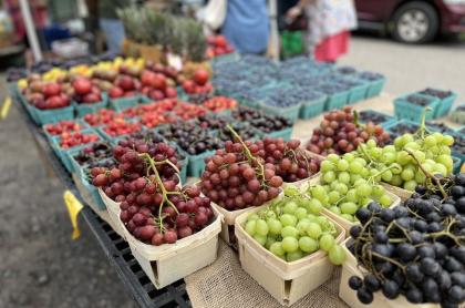 a table with a variety of fruit- grapes&#44; berries&#44; cherries&#44; in pint size containers