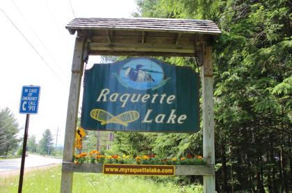 The sign that hangs by the roadside welcoming people to Raquette Lake