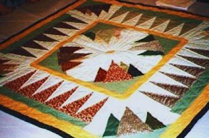 A photo of a adirondack quilt with mountain designs in a square quilt