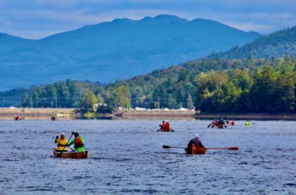 Long boat paddlers on the water with the mountains in the background