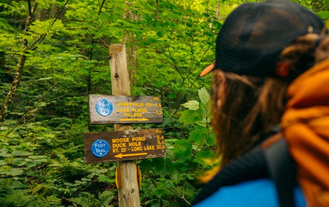 A man reads wooden signs along the NPT trail