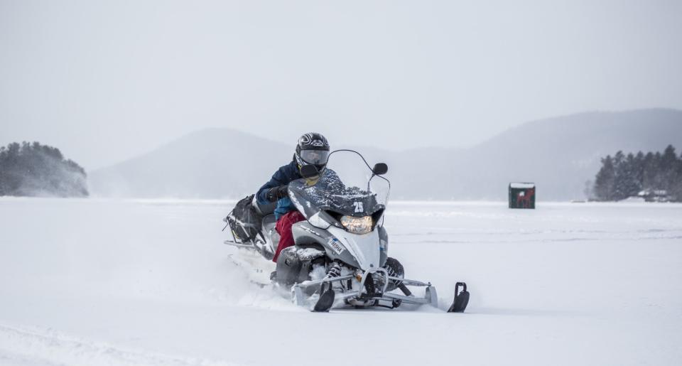 A snowmobiler drifting on a snowy lake.