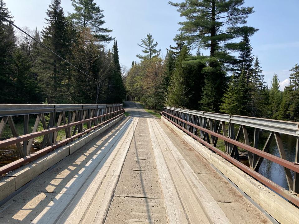 A wooden bridge over a stream leading into the forest.