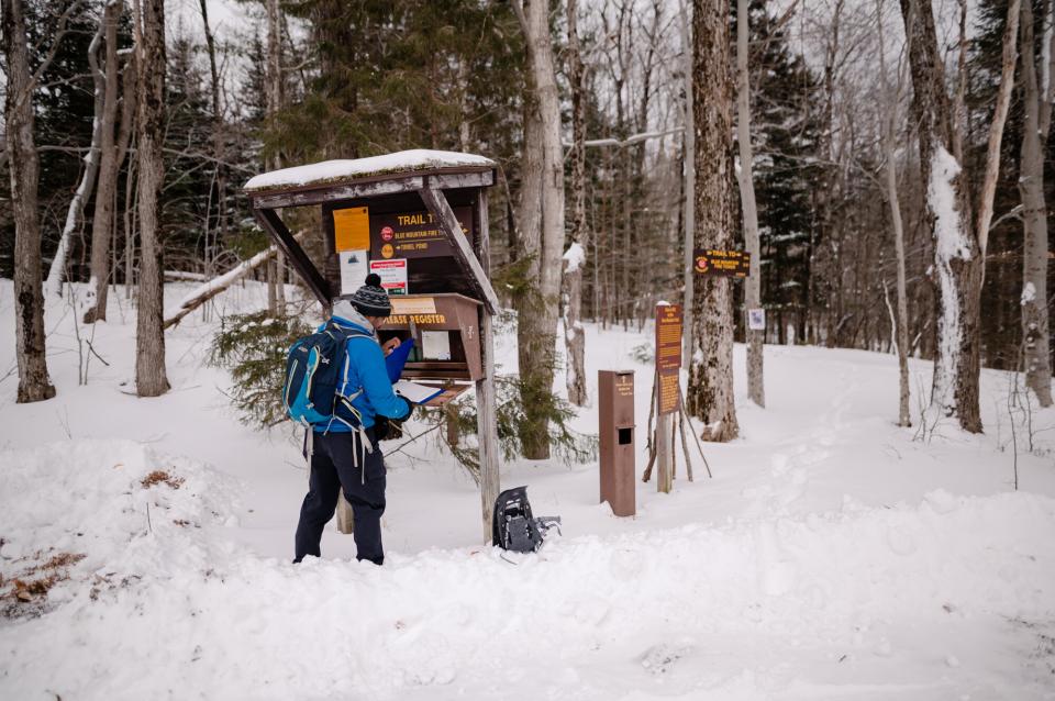 A man in a blue winter coat checks into a snowshoeing trail.