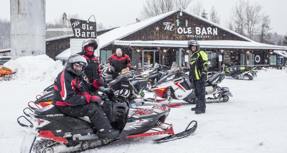 A group of snowmobilers parked outside of the Old Barn restaurant .