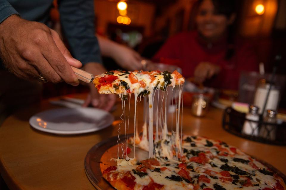 Close-up of a piece of gooey, cheesey pizza being served.