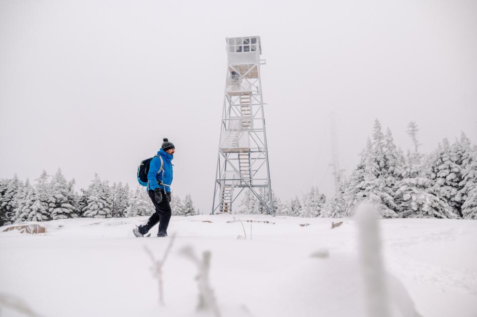 A snowshoer walking past a fire tower