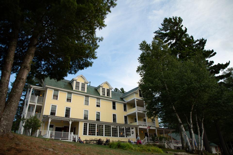 a yellow hotel and restaurant in between the trees.