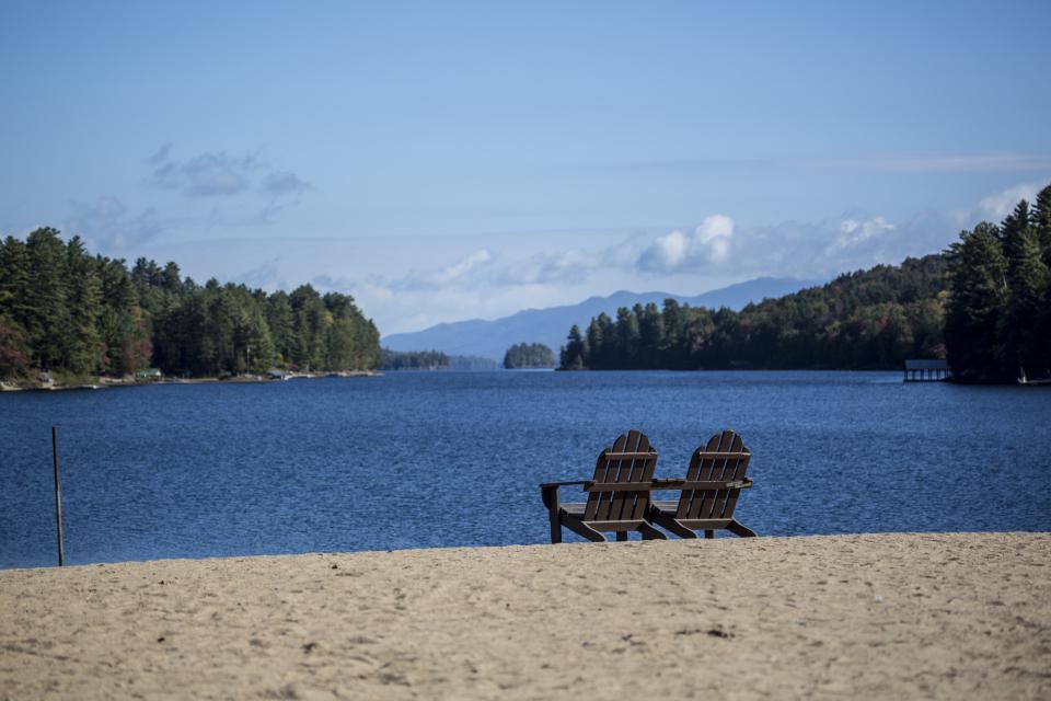 two adirondack chairs look out onto the lake and mountains.