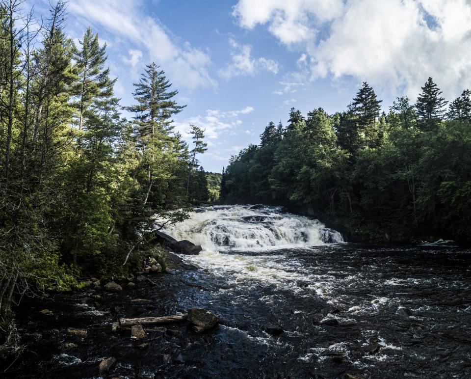 a waterfall rushes down into a stream.