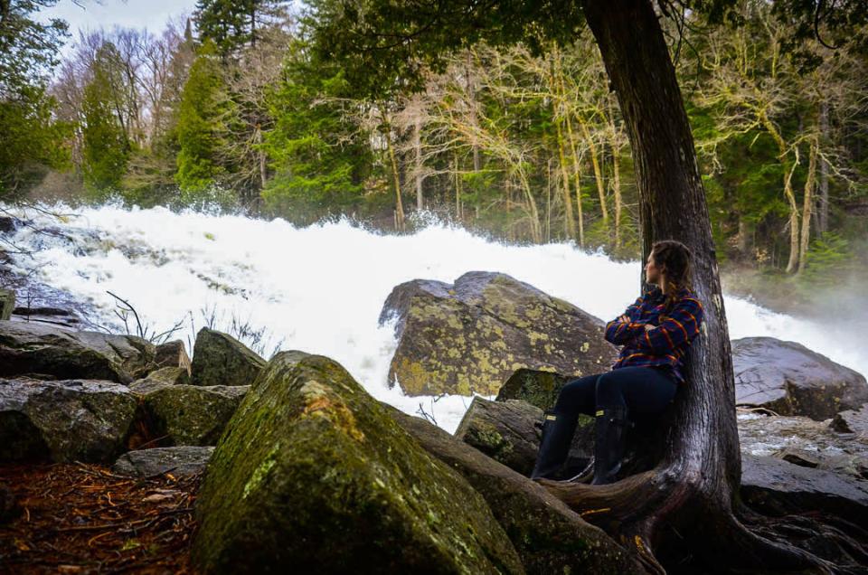 a woman rests next to a waterfall.