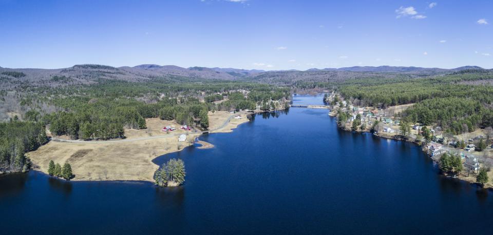 an aerial view of a lake, bridge, and farmland next to a town.