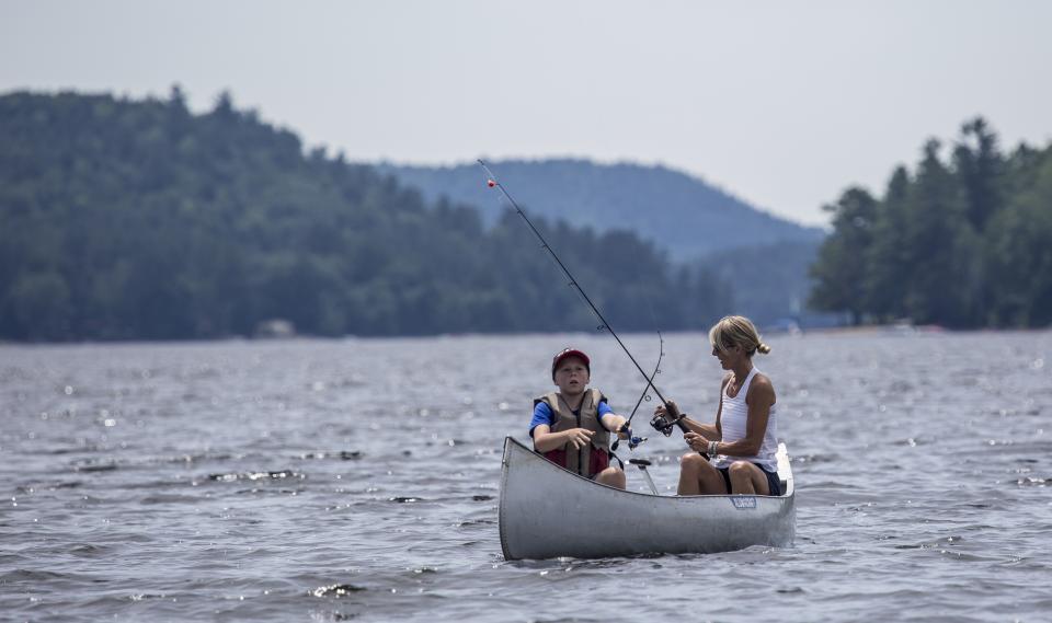 Boy and mother fishing from boat on lake