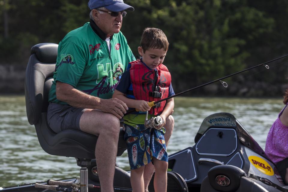 Boy fishing from boat with grandfather