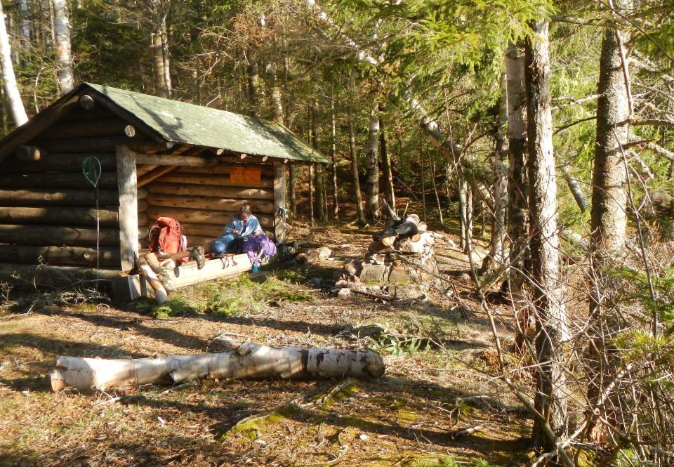 Two hikers in a lean-to on a sunny day.