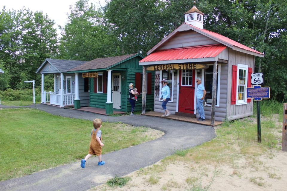 A toddler runs toward a display of miniature buildings.