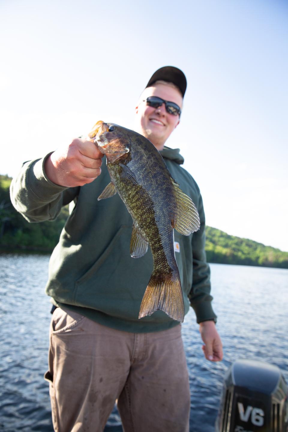 A man holds a bass on a boat.