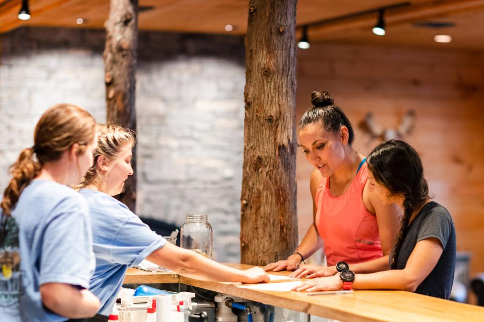 The bartenders at the Lemon Tree Brewery kindly talk two women through their different drink options on the menu