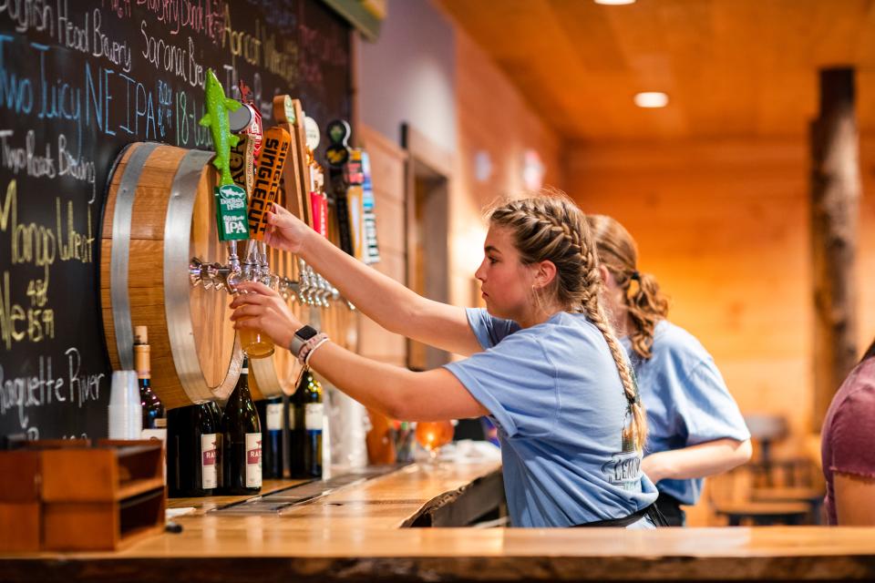 A bartender pouring beer out of taps.