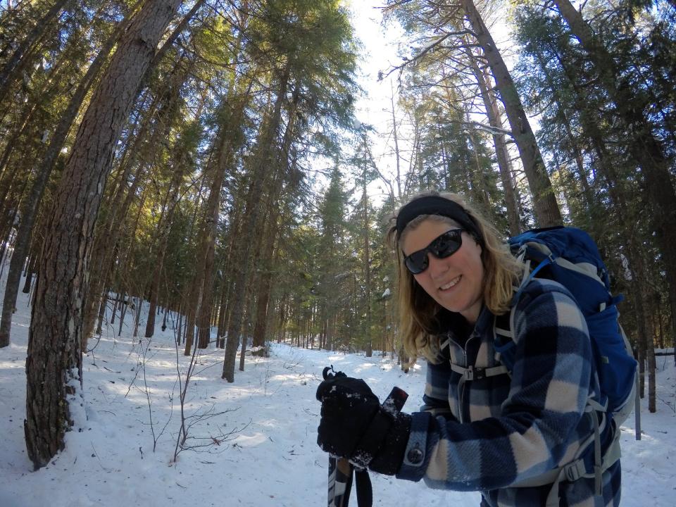 A woman wearing blue smiles for a photo during a cross-country ski trip.