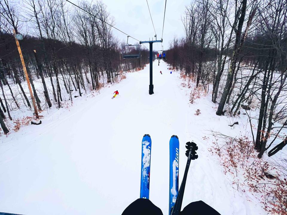 A skier rides the chairlift as others ski below.