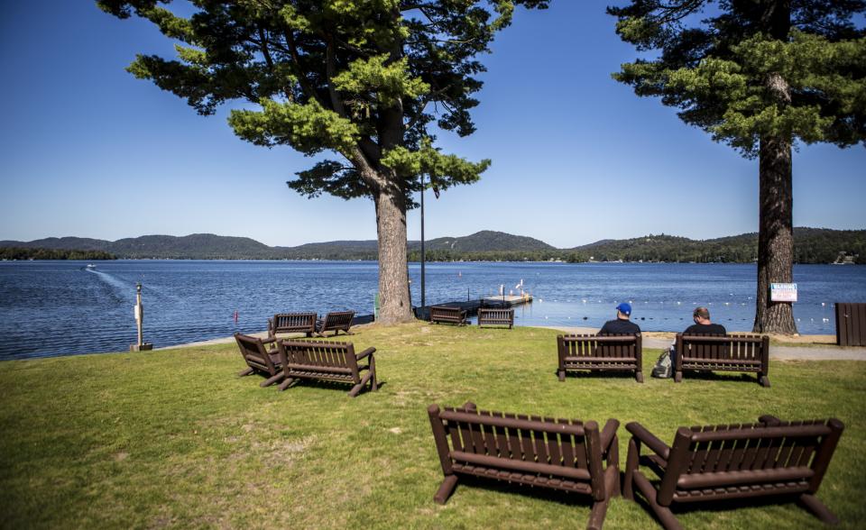 Benches overlooking a lake with mountain views on a sunny day.