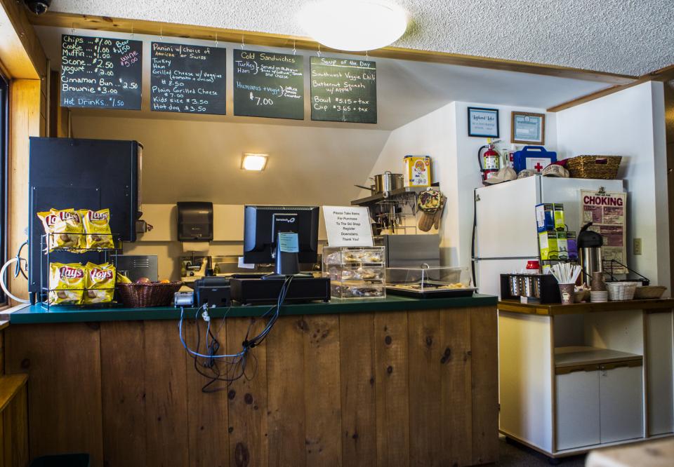 A food counter with a chalkboard menu on the wall and restaurant machinery.