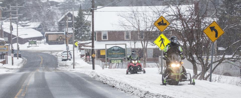 two people snowmobile out of town.