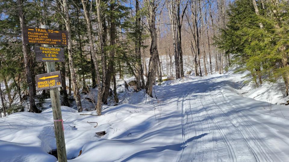 Sign pointing towards Pillsbury Mountain next to a snowy Nordic ski trail.