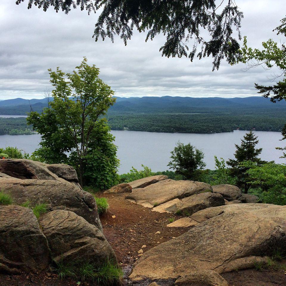 Looking down onto a broad lake and distant mountains from a rocky summit.