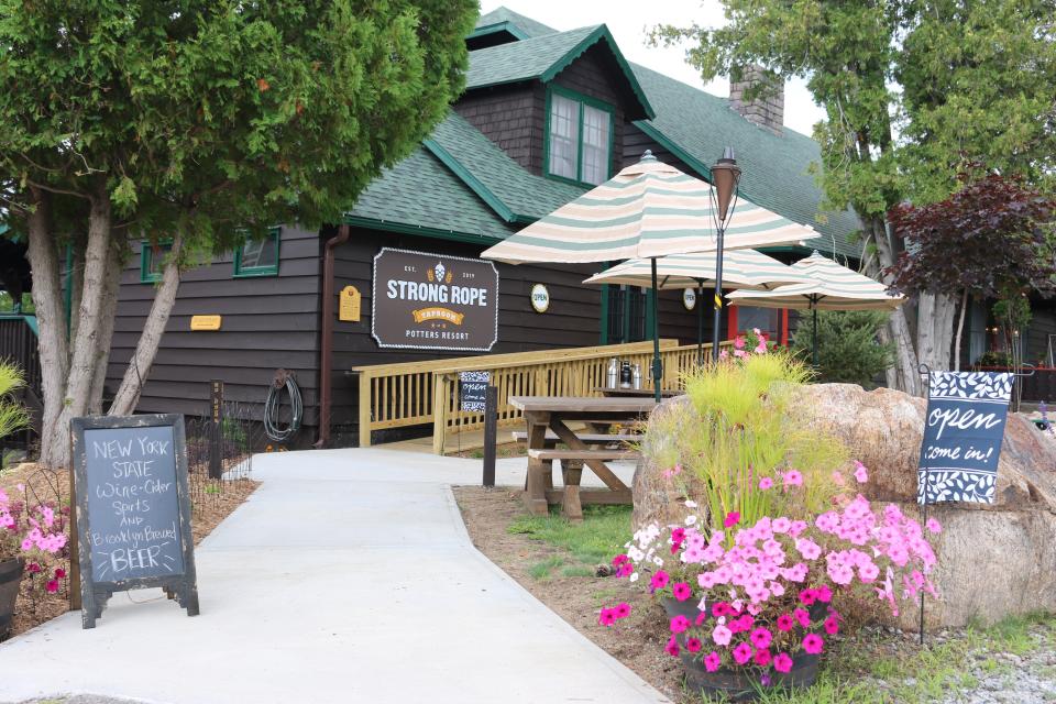 A brown cabin-style building with a concrete ramp and patio seating.