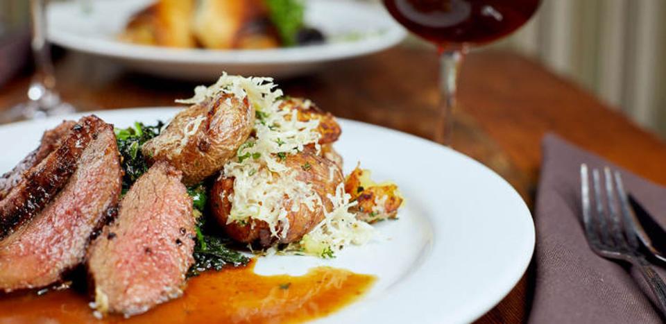 A close up of a high-end meal of meat and potatoes with a garnish on top.