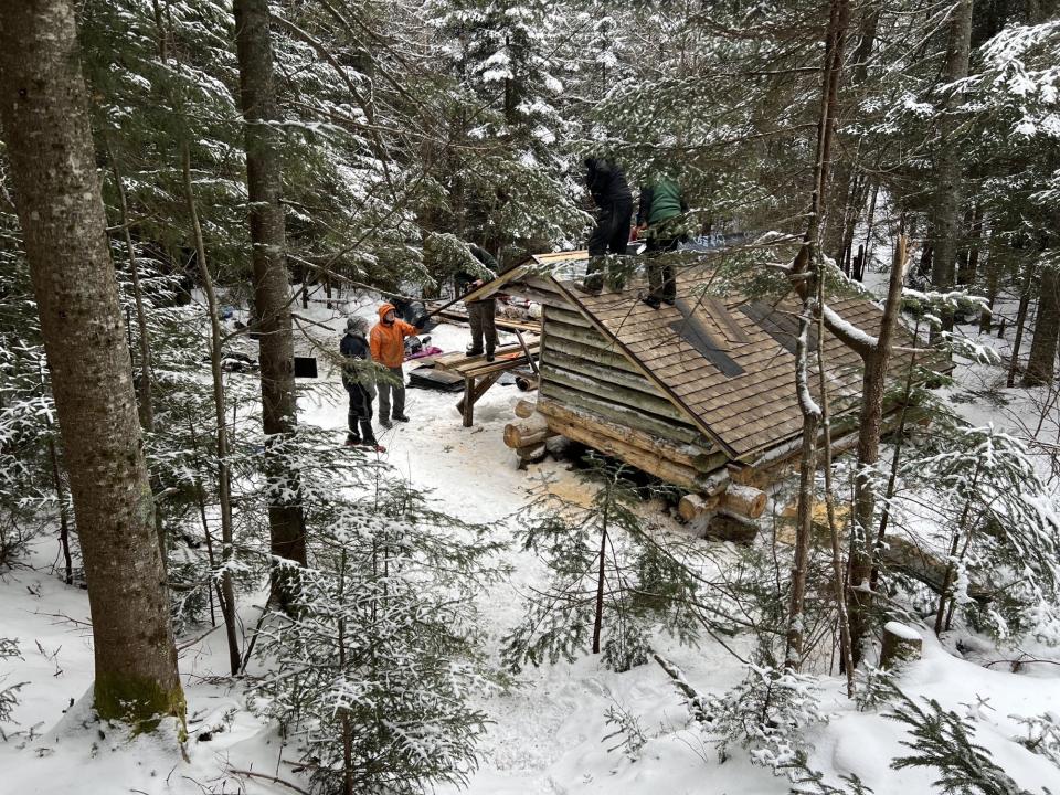 A group of workers fixing a wooden lean-to in the winter'