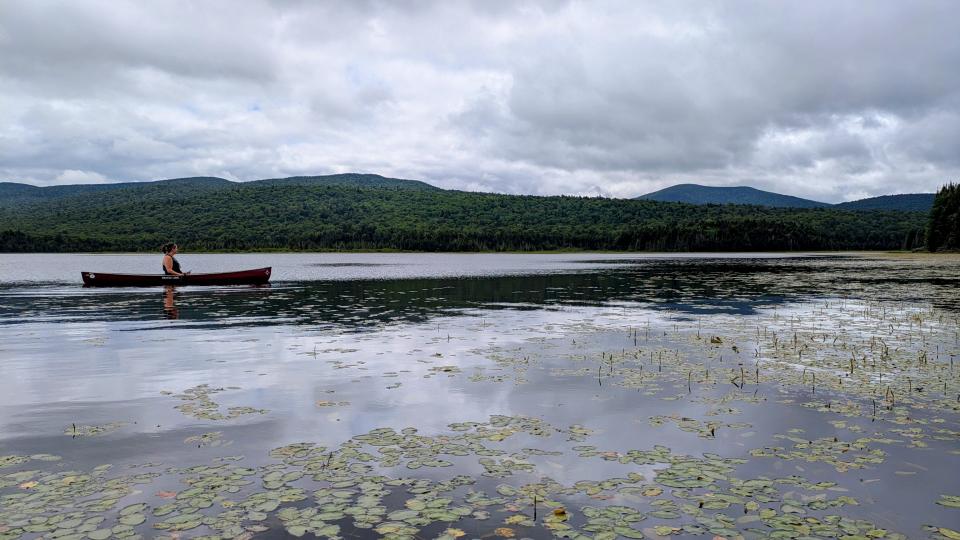 Woman in canoe looking at mountains in the distance.